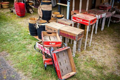 Vintage wooden crates and barrels displayed at an outdoor market, featuring Coca-Cola and Seven-Up branding.
