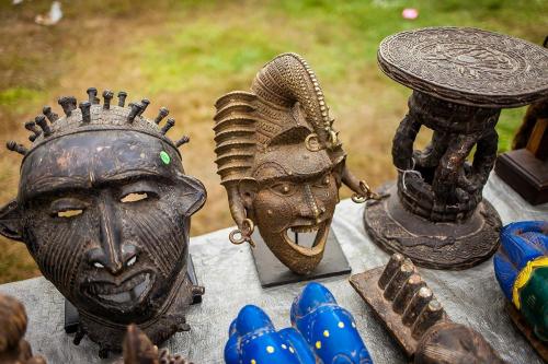 A display of various decorative masks and sculptures on a table, showcasing intricate designs and textures.