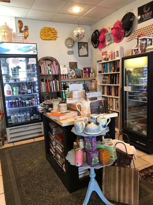 Cozy shop interior with bookshelves, a counter, and various products, including drinks and tea, in a welcoming atmosphere.