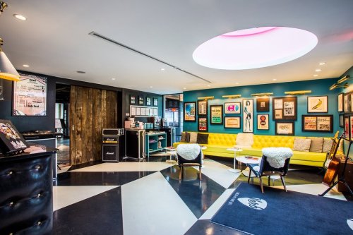 A stylish interior of a modern lounge with colorful decor, seating, and framed artwork on the walls.
