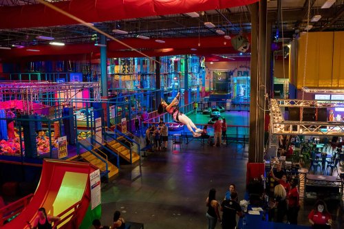 A vibrant indoor trampoline park with colorful play areas and people enjoying various activities.