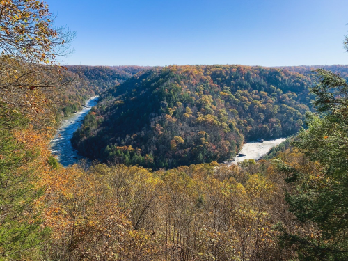 A scenic view of a river winding through colorful autumn hills under a clear blue sky.