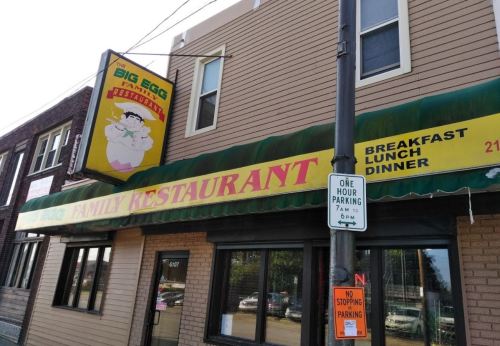 Exterior of The Big Egg Family Restaurant, featuring a colorful sign and a parking sign nearby.