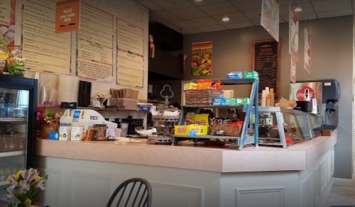A cozy café counter with a display of snacks, drinks, and a menu on the wall, featuring a welcoming atmosphere.
