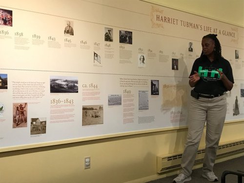 A guide stands beside a timeline exhibit detailing Harriet Tubman's life and achievements.