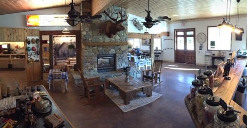 Cozy interior of a rustic café with a stone fireplace, wooden furniture, and a welcoming atmosphere.