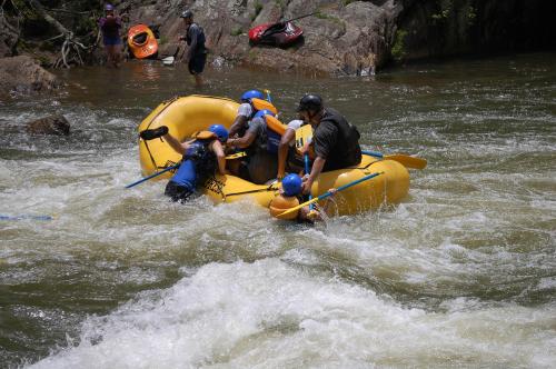 A group of people in a yellow raft navigating rough waters, with some members leaning over the side.