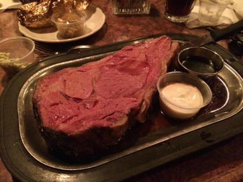 A large, juicy prime rib served on a sizzling platter with dipping sauces on the side.