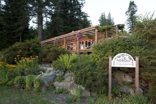 A wooden building surrounded by lush greenery and flowers, with a sign reading "The Willow's Inn."
