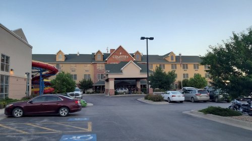 Exterior view of a Country Inn hotel with a water slide, surrounded by trees and parked cars in the foreground.