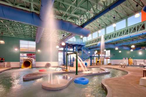 Indoor water park featuring slides, a lazy river, and water features under a bright, spacious ceiling.