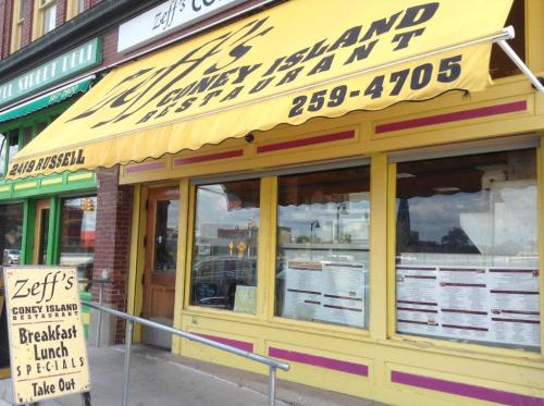 A bright yellow awning with "Zeff's Coney Island Restaurant" over a storefront featuring a menu display.