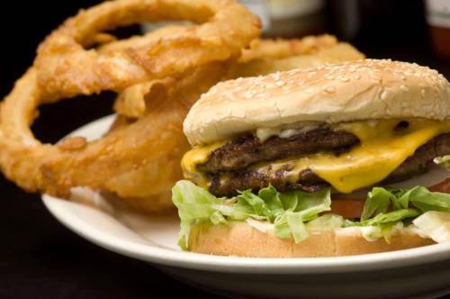 A juicy cheeseburger with lettuce and tomato, served with crispy onion rings on the side.