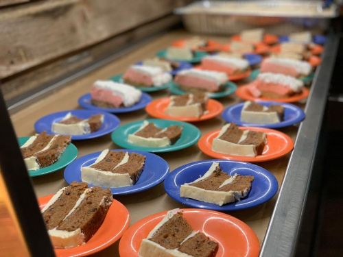A variety of cake slices on colorful plates, arranged neatly on a table.
