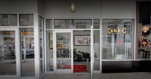 Entrance of a restaurant with glass doors, featuring a red carpet and decorative signage.