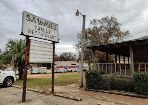 Sign for Sawmill Family Restaurant with a cloudy sky and a view of the building and surrounding area.