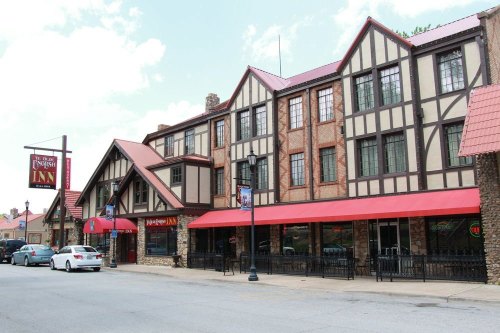 A charming Tudor-style inn with a red roof and outdoor seating, located on a street with parked cars.