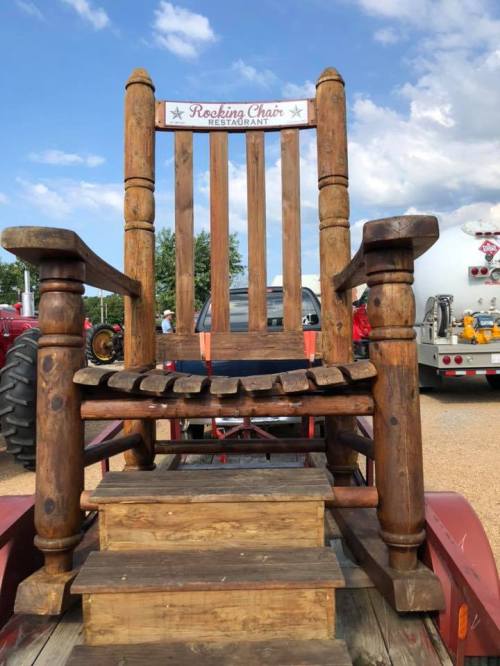 A large wooden rocking chair on a trailer, with a sign reading "Rocking Chair Restaurant" above it.