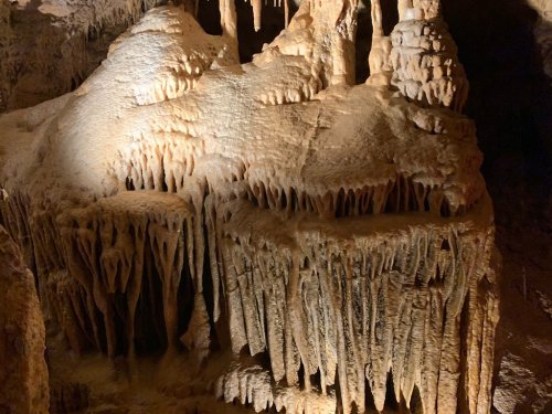 Stalactites and stalagmites in a dimly lit cave, showcasing intricate rock formations.