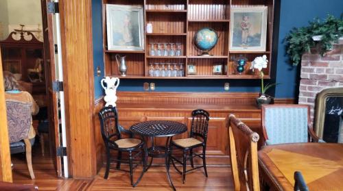 A cozy corner with two black chairs and a small table, surrounded by wooden shelves and decorative items.