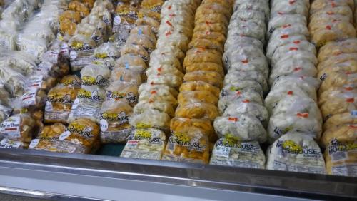 A display of various packaged dumplings in a freezer section, arranged in neat rows.
