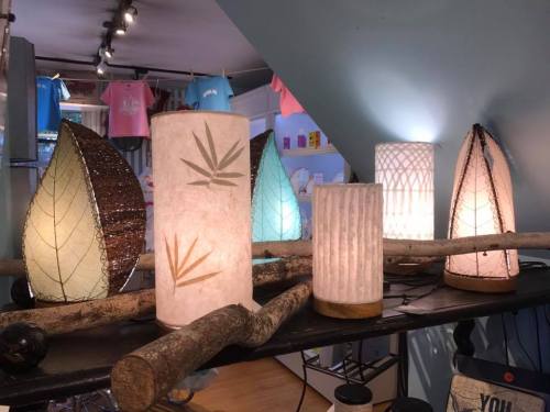 A display of unique decorative lamps in various shapes and designs, illuminated on a wooden shelf.