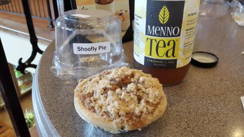 A slice of shoofly pie next to a bottle of Menno Tea on a countertop.