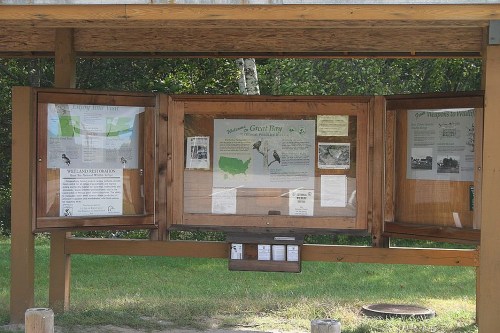 Information display board at a nature site, featuring maps and educational materials about local wildlife and habitats.