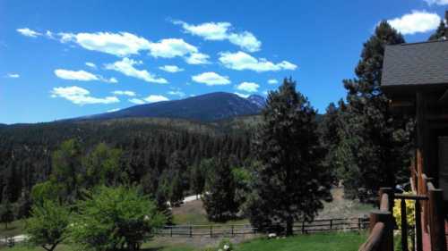 A scenic view of mountains and trees under a blue sky with fluffy clouds.