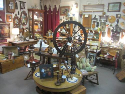 A cozy antique shop filled with vintage items, including a spinning wheel, furniture, and various collectibles.