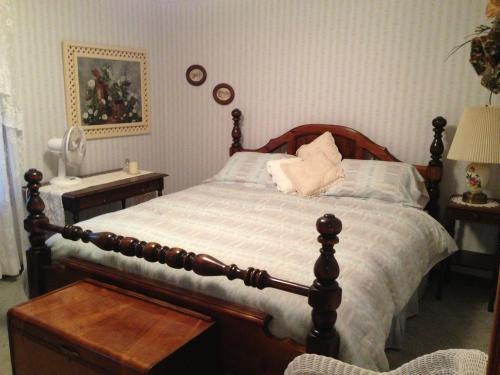 A cozy bedroom featuring a wooden bed, light blue bedding, a nightstand, and decorative wall art.
