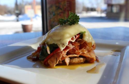 A plated dish featuring a savory stack of ham, spinach, and melted cheese on a mushroom cap, garnished with parsley.