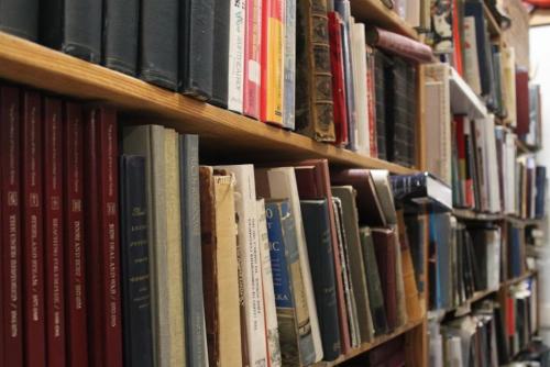 A close-up of a wooden bookshelf filled with various books in different colors and sizes.