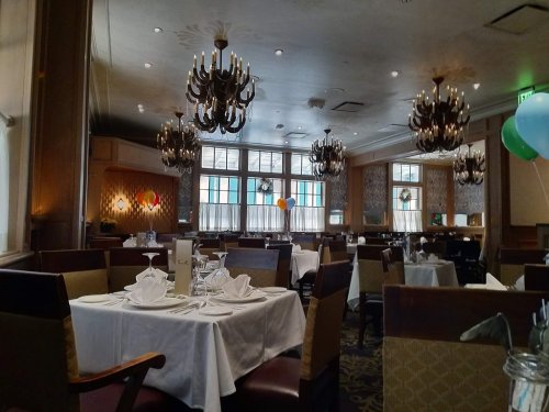 Elegant restaurant interior with chandeliers, neatly set tables, and festive decorations.