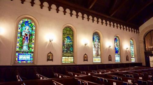 Interior of a church featuring colorful stained glass windows and wooden pews.