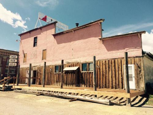 A pink building with wooden accents, labeled "Post Hotel," set against a blue sky with scattered clouds.