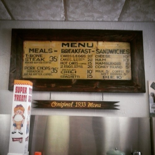 Vintage menu board featuring prices for meals, breakfast items, and sandwiches from a diner.
