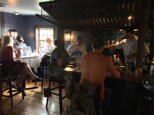 A cozy restaurant scene with diners at tables and a bartender serving drinks in a warm, inviting atmosphere.