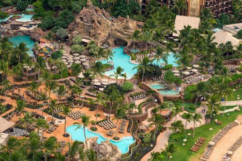 Aerial view of a tropical resort with multiple pools, palm trees, and lounge chairs surrounded by lush landscaping.