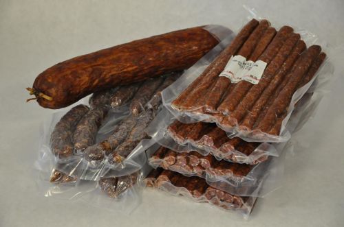 Assorted packaged sausages, including a large log and several smaller sticks, displayed on a light background.
