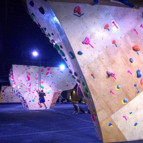 Indoor climbing gym with colorful bouldering walls and climbers engaged in various climbing activities.