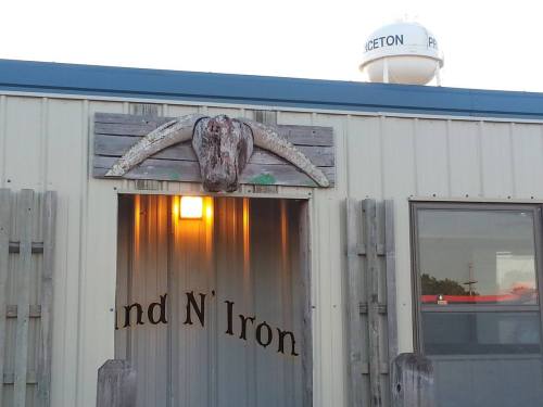 A rustic building entrance with a cow skull decoration and a water tower in the background.