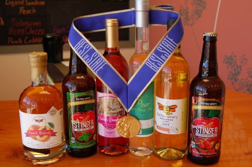 A collection of various bottles of wine and spirits, featuring a medal and ribbon labeled "Best in State."
