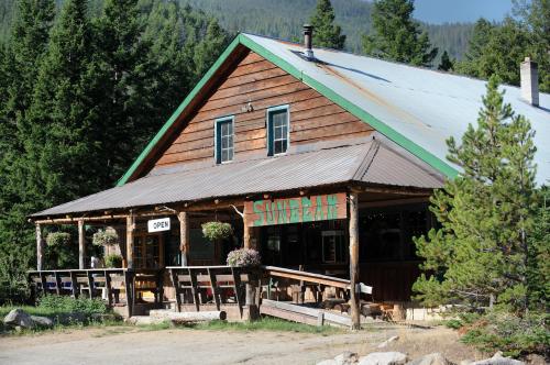 A rustic wooden building with a green roof, labeled "Sunbeam," surrounded by trees and flowers, with an "Open" sign.