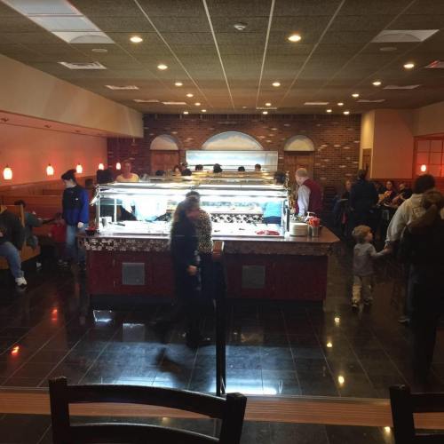 A busy restaurant interior with a buffet counter, diners seated at tables, and a warm, inviting atmosphere.