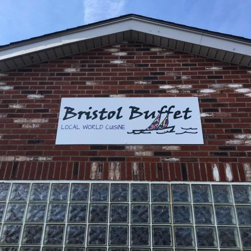 Sign for "Bristol Buffet" featuring the text "Local World Cuisine" on a brick building with glass block windows.