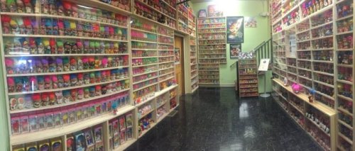 A colorful room filled with shelves of various troll dolls, showcasing a vibrant collection along the walls.
