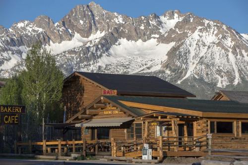 A rustic café and bakery with a wooden exterior, set against a backdrop of snow-capped mountains and clear blue skies.