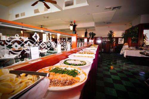 A buffet spread featuring various dishes, including pasta, vegetables, and seafood, in a restaurant setting.