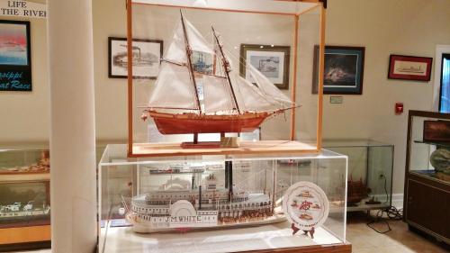 Model ships displayed in a museum, featuring a sailing ship and a steamboat, with informative plaques nearby.